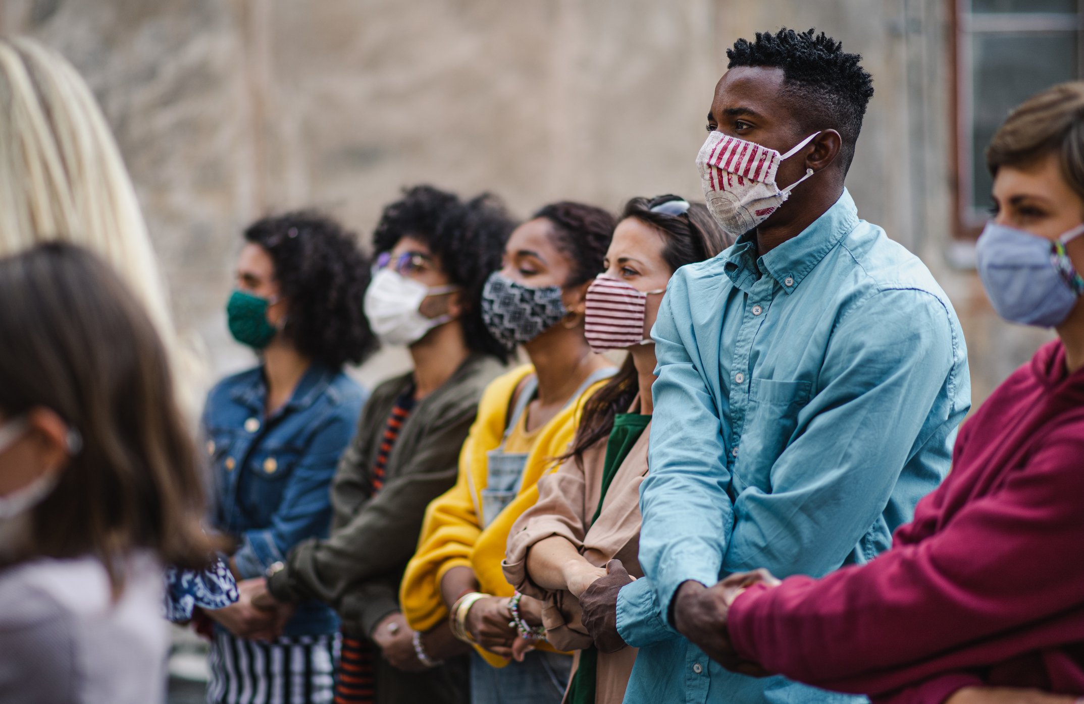 Activists holding hands wearing masks